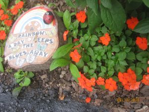 Garden art featuring a stump, a rainbow, and the text "A Rainbow Keeps the Blues Away"